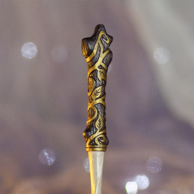 May include: A wooden wand with a dark brown finish and gold accents. The wand is decorated with a vine-like pattern.