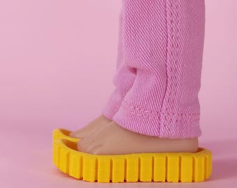 May include: A close-up of a doll's feet wearing yellow platform sandals, paired with pink pants. The sandals have a ridged sole. The number 7 is printed in white on the bottom right corner of the image. The background is a solid pink.