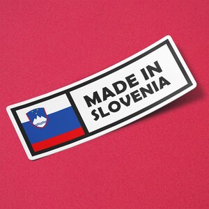 May include: A white sticker with a black border and the text "MADE IN SLOVENIA" in black. The sticker features the Slovenian flag, with a white, blue, and red design, and a coat of arms.