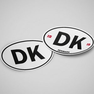 May include: Two white oval stickers with black text that reads "DK" and the word "DENMARK" in smaller text below. The stickers have a red and white Danish flag on either side of the text.
