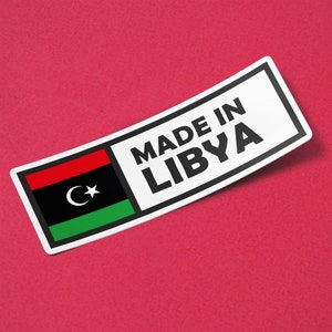 Puede incluir: Una pegatina blanca con texto negro que dice "Made in Libya". La pegatina presenta la bandera de Libia con un esquema de colores verde, negro y rojo y una luna creciente y una estrella.