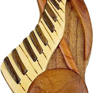 May include: A wooden puzzle box shaped like a piano with a round lid. The piano keys are made of wood and the box is made of a dark brown wood.