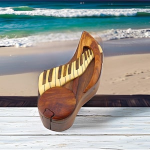 May include: A wooden puzzle box shaped like a treble clef with a piano keyboard design. The box is made of dark wood with a light wood inlay for the keys. The box is sitting on a white wooden surface.