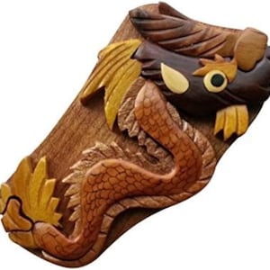 May include: A wooden puzzle box shaped like a dragon. The dragon is intricately carved with brown, gold, and black wood. The box is closed and has a secret opening.