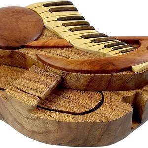 May include: A wooden puzzle box shaped like a grand piano with a hinged lid and multiple interlocking pieces. The box is made of light and dark wood and has a natural finish.