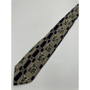 May include: A black and beige patterned tie with a geometric design. The tie has a pointed tip and is made of a silky material.