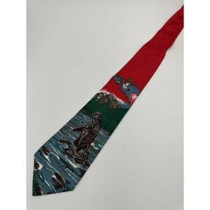 May include: A red silk tie with a printed design of a sea otter swimming in the ocean, a mountain, and a bird flying overhead.