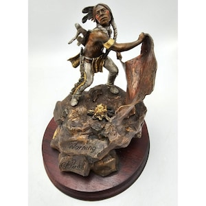May include: Bronze sculpture of a Native American man holding a red cloth, standing on a rocky base. The sculpture is signed "Warning C.T. Pardell".