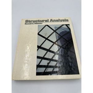 May include: A white book with the title "Structural Analysis" by Russell C. Hibbeler. The cover features a photograph of a modern building under construction, with a view of the sky through the steel beams.