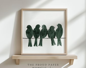 May include: A square framed wall art piece featuring a watercolor illustration of five dark green birds perched on a single horizontal black line. The text below the frame reads THE PROUD PAPER Handcrafted Watercolors.