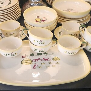 Peut inclure: Un ensemble vintage de tasses à thé et de soucoupes sur le thème de la ferme. Les tasses et les soucoupes sont blanches avec des motifs floraux verts et rouges. L'ensemble comprend un plateau de service avec une scène de ferme.