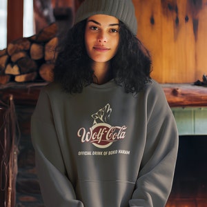 May include: A dark gray sweatshirt with a red and white logo that says "Wolf-Cola" and the text "Official Drink of Boko Haram".