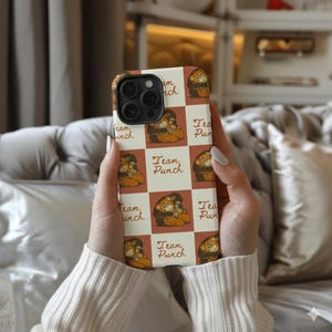 May include: A phone case with a repeating pattern of a cartoon monkey hugging another monkey, set against a white and brown checkered background. The words "Team Punch" are also displayed on the case.