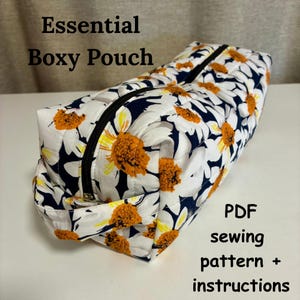 May include: Boxy pouch with a white daisy floral pattern on a navy blue background. The pouch has a black zipper and is labeled "Essential Boxy Pouch" and "PDF sewing pattern + instructions".