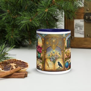 May include: A white ceramic mug with a blue interior, featuring a detailed illustration. The design includes flowers, books, a raven, and the words "Computer Science" and "The Raven". The mug has a gold and blue color scheme.