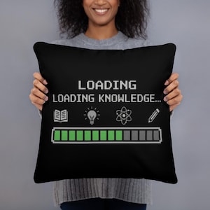 May include: Black square pillow with the text "LOADING LOADING KNOWLEDGE..." in white. Below the text are icons of a book, lightbulb, atom, and pencil. A green and gray loading bar is at the bottom.