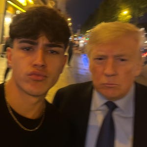 Puede incluir: Un selfie con dos personas. Uno es un joven con cabello oscuro y una cadena de oro. El otro es un hombre mayor con cabello rubio, que lleva un traje y una corbata. El fondo es una escena nocturna borrosa al aire libre.