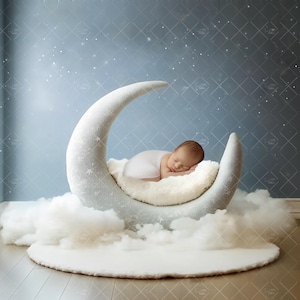 May include: A newborn baby sleeping peacefully in a white crescent moon prop, nestled on a fluffy, cream-colored surface. The moon is surrounded by soft, white clouds, set against a blue backdrop with a starry pattern. A perfect photo prop for newborn photography.