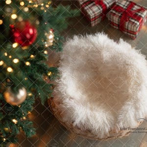 May include: A Christmas-themed newborn photography backdrop. Features a woven basket with a fluffy white insert, a decorated Christmas tree with ornaments and lights, and two wrapped gifts with red ribbons.