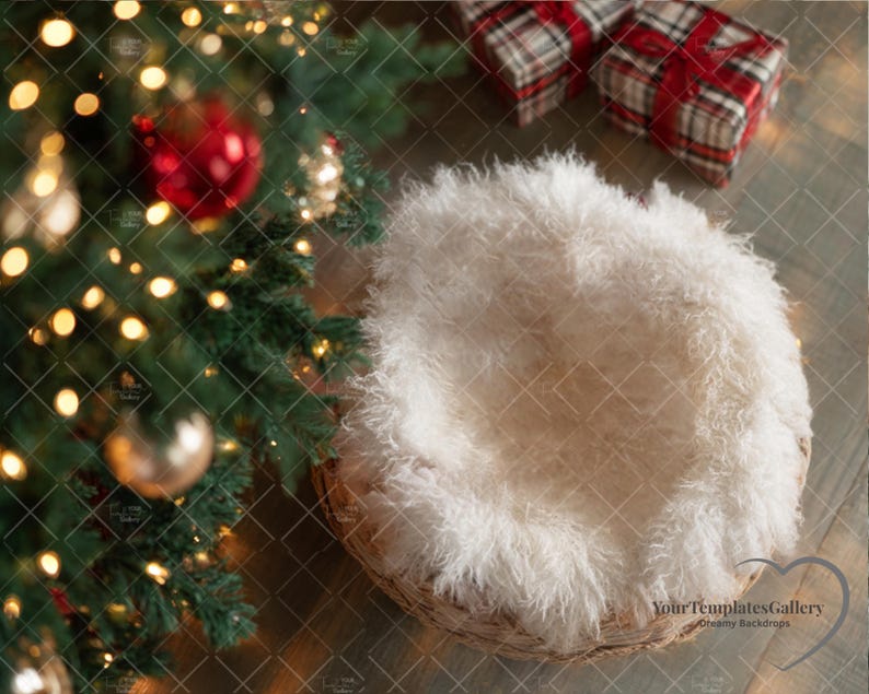 May include: A Christmas-themed newborn photography backdrop. Features a woven basket with a fluffy white insert, a decorated Christmas tree with ornaments and lights, and two wrapped gifts with red ribbons.