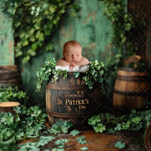 May include: A sleeping baby is nestled in a wooden barrel decorated with green leaves and the text "St. Patrick's Day". The barrel is surrounded by green leaves and shamrocks.