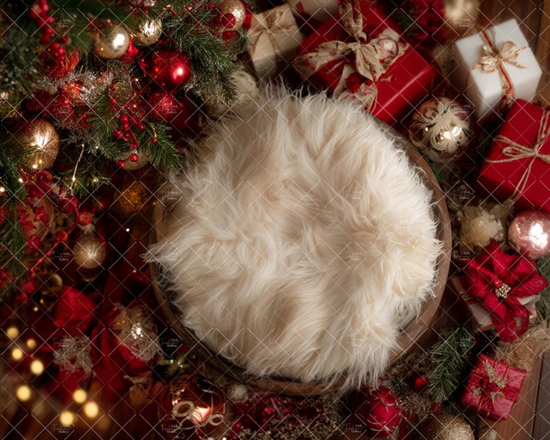 May include: A festive Christmas-themed newborn photography prop setup. Features a wooden bowl filled with fluffy cream-colored faux fur, surrounded by red and gold ornaments, wrapped gifts, and evergreen branches.
