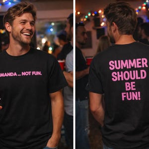 Puede incluir: Camiseta negra con texto rosa que dice "AMANDA... NOT FUN." en la parte delantera y "SUMMER SHOULD BE FUN!" en la parte trasera. La persona lleva la camiseta en un ambiente social, sosteniendo una taza roja.