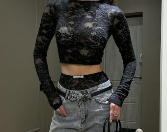 Zweiteiliges Set aus schwarzer Spitze – transparentes, langärmeliges Crop-Top und hochgeschnittene Shorts.