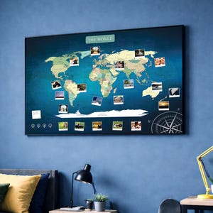Op de afbeelding: Een wereldkaart met een blauwe achtergrond en een zwarte lijst. De kaart toont verschillende landen in verschillende kleuren, met kleine foto's erop gespeld. De tekst "THE WORLD" staat bovenaan en een kompasroos rechtsonder.