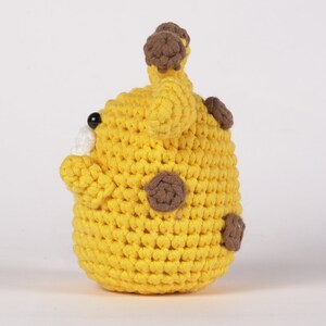 May include: A yellow crocheted giraffe toy with brown spots and ears. The toy is made of soft yarn and is perfect for cuddling.