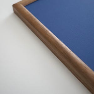 Puede incluir: Primer plano de un marco de madera marrón oscuro que enmarca una superficie azul profundo texturizada. El marco está en ángulo, mostrando la esquina y el perfil lateral. El fondo es blanco. Las dimensiones del marco son en centímetros.