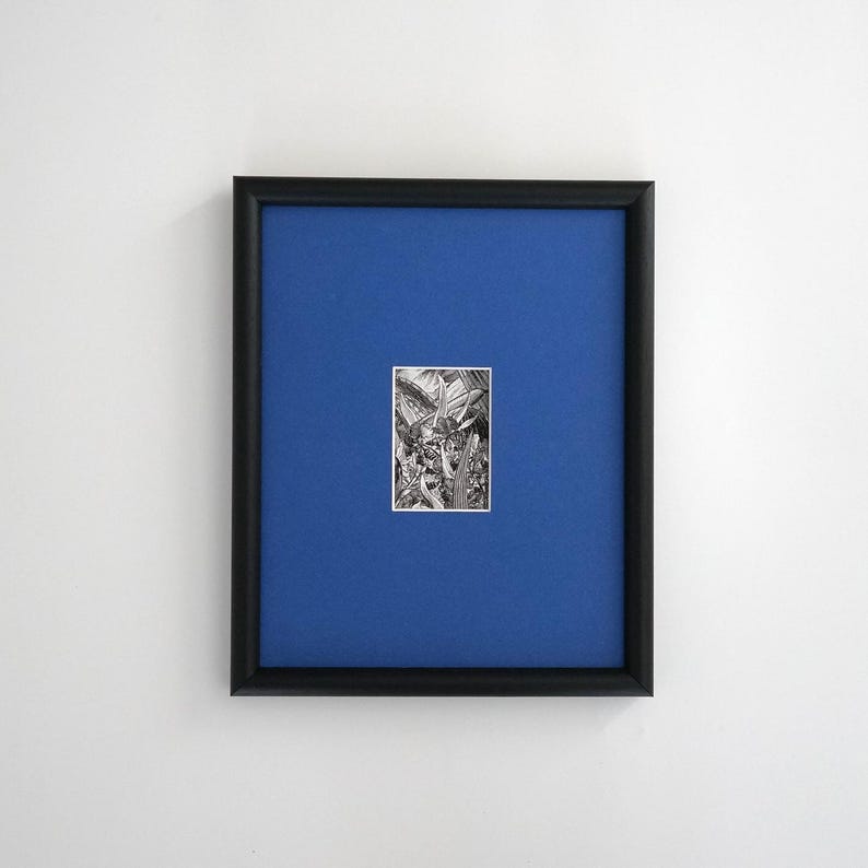 May include: A framed artwork featuring a small black and white illustration centered on a vibrant blue background. The frame is black, and the artwork appears to be a detailed drawing of plants or foliage. The overall aesthetic is minimalist and modern.