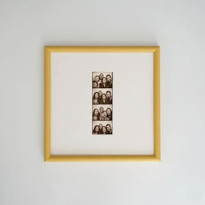 Peut inclure: Une photo encadrée avec quatre séries d'images en noir et blanc de groupes de personnes. Le cadre est de forme carrée avec une finition jaune, et la bande photo est centrée sur un fond blanc.