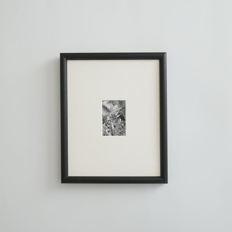 May include: A framed black and white botanical print. The artwork features a detailed illustration of plants and foliage. The print is set within a white mat and a black frame, creating a classic and elegant presentation.