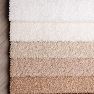 Könnte beinhalten: Nahaufnahme eines Stoffmusters mit sechs verschiedenen Beige- und Brauntönen. Der Stoff hat ein strukturiertes, flauschiges Aussehen mit einem weichen, plüschigen Gefühl. Die Farben reichen von hellem Creme bis zu tiefem Braun.