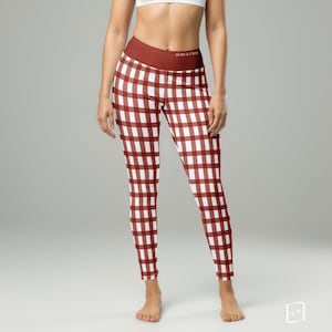 May include: Red and white gingham leggings with a wide, dark red waistband. The leggings have a classic checkered pattern and are made of a stretchy material. The text "Hom & Rose" is printed on the waistband.