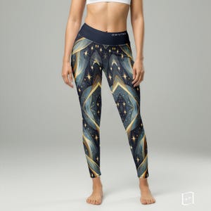 May include: Navy blue leggings with a celestial design. The leggings feature a pattern of gold and blue geometric shapes, stars, and the text "Hood & Frame" on the waistband. The leggings are form-fitting and reach the ankles.