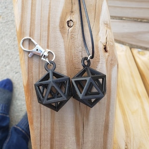 May include: Two black geometric pendant necklaces, one on a silver chain and the other on a black cord. The pendants are shaped like a three-dimensional geometric shape, resembling a dice.