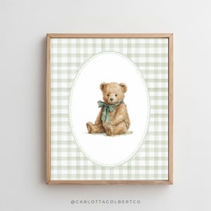 May include: A framed print featuring a watercolor illustration of a teddy bear. The bear is light brown with a green bow, set against a green and white gingham background within an oval frame. The frame is made of wood.