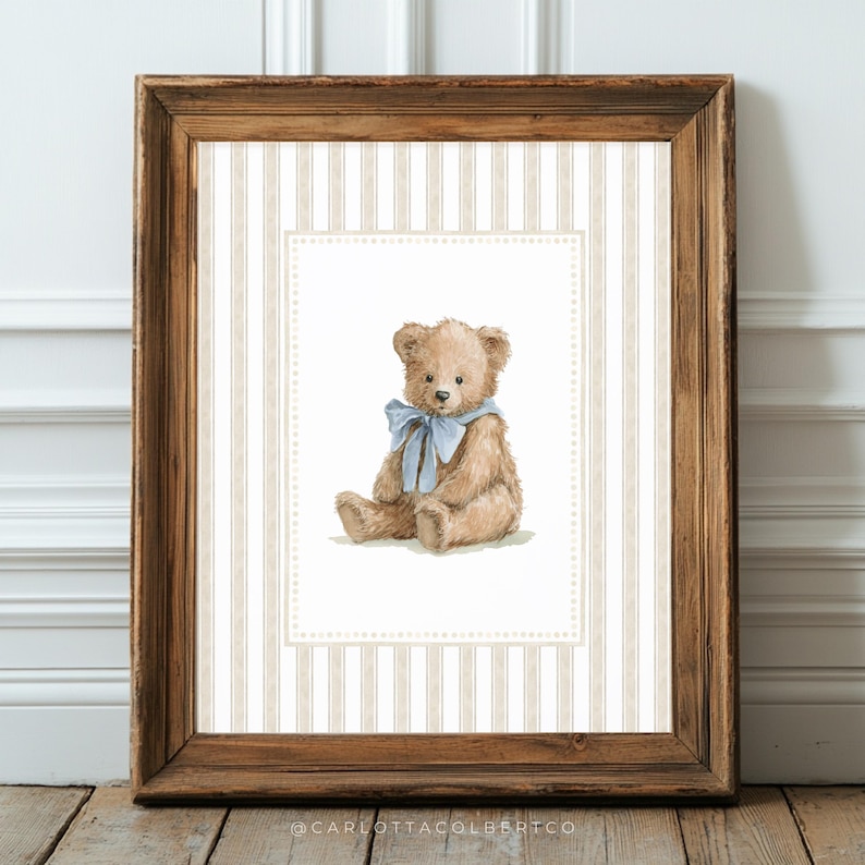 May include: A framed print featuring a watercolor illustration of a teddy bear with a blue ribbon. The bear is light brown, set against a striped background in a wooden frame. The artwork is a charming piece of nursery decor.