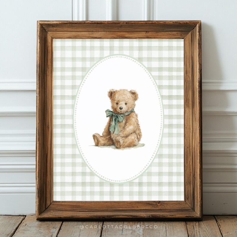 May include: A framed print featuring a watercolor illustration of a teddy bear. The bear is light brown with a green bow, set against a green and white gingham background within an oval frame. The wooden frame adds a rustic touch.