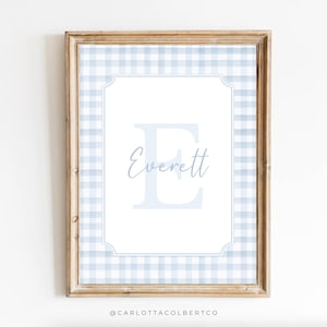 May include: A framed print featuring the name "Everett" in a soft blue script, with a large blue "E" initial. The background has a light blue and white gingham pattern. The frame is made of light brown wood.