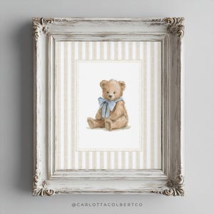 May include: A framed print featuring a watercolor illustration of a teddy bear with a blue ribbon. The bear is set against a striped background within a white ornate frame. The artwork has a vintage aesthetic.