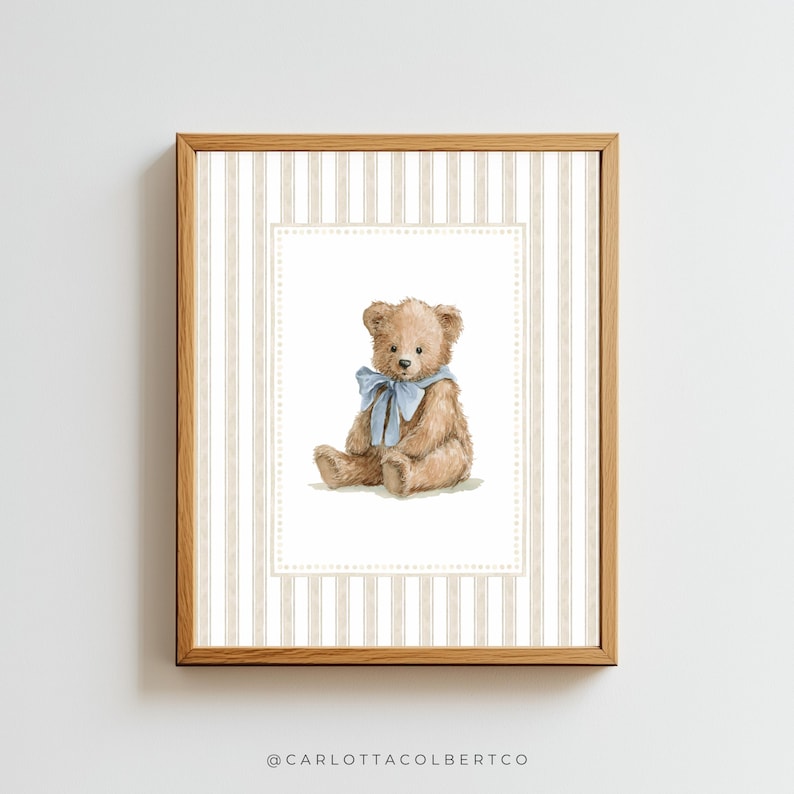 May include: A framed print featuring a watercolor illustration of a teddy bear. The bear is light brown with a blue ribbon around its neck. The background has a striped pattern in beige and white.