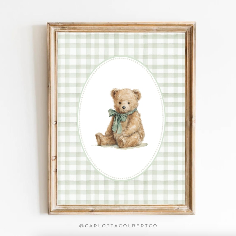 May include: A framed print featuring a watercolor illustration of a teddy bear. The bear is light brown with a green bow, set against a white oval on a green and white gingham background. The frame is a light brown color.