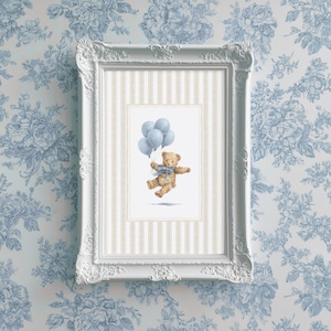 K&ouml;nnte beinhalten: Ein gerahmter Druck mit einer Aquarellillustration eines Teddyb&auml;ren, der blaue Luftballons h&auml;lt. Der B&auml;r hat eine blaue Schleife und befindet sich vor einem gestreiften Hintergrund in einem wei&szlig;en, verzierten Rahmen. Der Hintergrund ist eine blaue Blumentapete.
