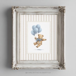 K&ouml;nnte beinhalten: Ein gerahmter Druck mit einer Aquarellillustration eines Teddyb&auml;ren, der blaue Luftballons h&auml;lt. Der B&auml;r hat eine blaue Schleife und schwebt. Der Rahmen ist wei&szlig; mit aufwendigen Details und einem gestreiften Hintergrund.