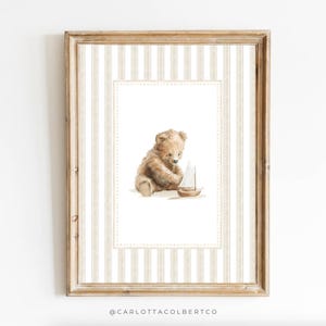 May include: A framed watercolor print featuring a brown teddy bear playing with a small sailboat. The artwork is set against a striped background in beige and white, with a decorative border. The frame is a light brown color.