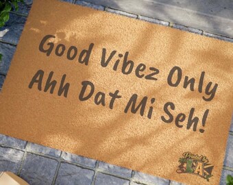 Puede incluir: Una alfombra rectangular con el texto "Good Vibez Only Ahh Dat Mi Seh!" en letras marrones oscuras. La alfombra es de color marrón claro y está sobre una superficie de piedra gris. El logotipo "Printed by LA" está en la esquina inferior derecha.