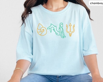 May include: A light blue t-shirt with a yellow seashell, green mermaid, and yellow trident graphic.